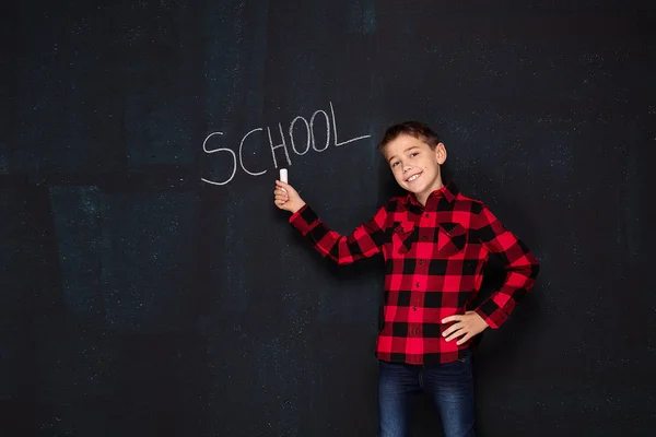 Мальчик-подросток в клетчатой рубашке на черной доске . — стоковое фото