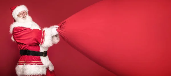 Real Santa Claus sonriendo, sosteniendo gran bolsa de regalo . —  Fotos de Stock