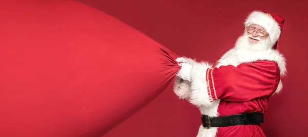 Справжній Санта Клаус посміхається, тримаючи великий сумочку з подарунками.. — стокове фото