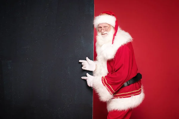 Πραγματικός Άγιος Βασίλης δείχνει σε μαύρο άδειο πίνακα. — Φωτογραφία Αρχείου