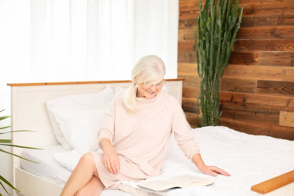 Ηρεμία Όμορφη Ηλικιωμένη Γυναίκα Κάθεται Στο Κρεβάτι Βιβλίο Χαλαρώνοντας Απολαμβάνοντας — Φωτογραφία Αρχείου