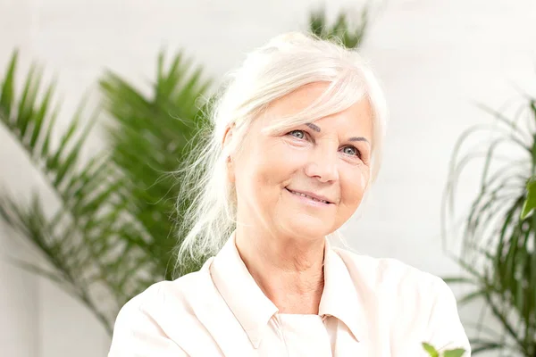 Evdeki Gülümseyen Yaşlı Bayanın Portresi Arka Planda Yeşil Bitkiler — Stok fotoğraf