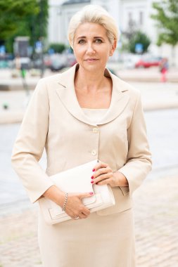 Zarif iş kadını gülümsüyor, dışarıda poz veriyor..