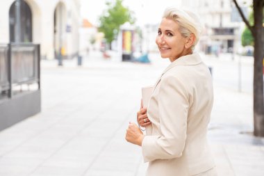 Zarif iş kadını gülümsüyor, dışarıda poz veriyor..