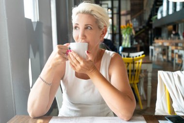 Kafeteryada kahve içen olgun bir kadın..