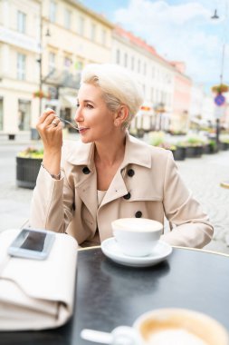 Güzel olgun bir kadının portresi kafeteryada bir fincan kahve içiyor.. 
