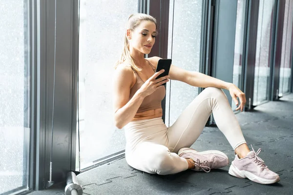 Woman in the gym after workout ,using mobile phone.