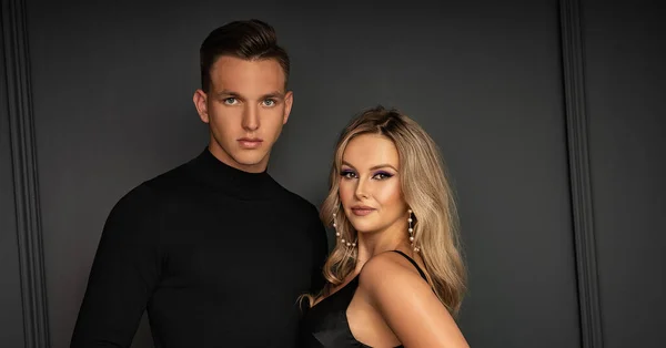 Young beautiful elegant couple posing on black background.