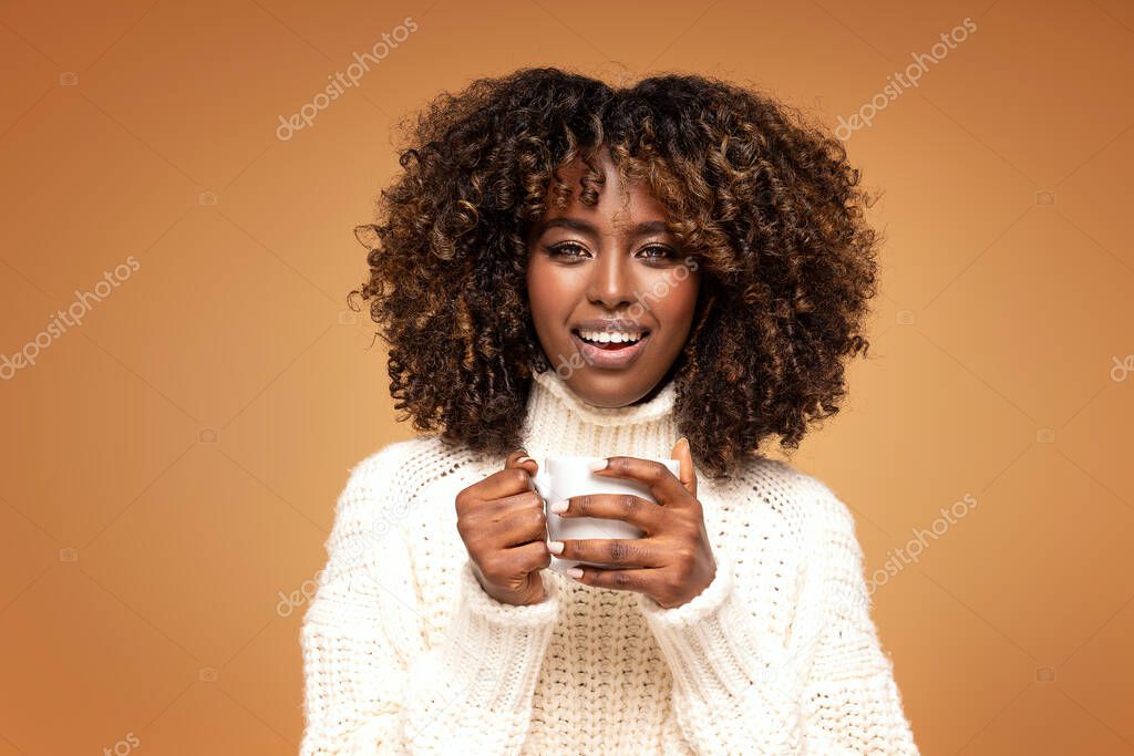 Happy ,beautiful afro woman holding coffee cup, looking at camera and smiling.