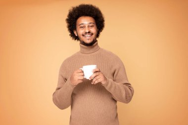 Afrikalı adam gülümsüyor ve elinde kahve fincanı tutuyor.