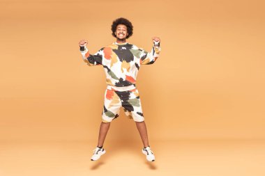 Neşeli genç afro adam havaya atlarken eğleniyor..