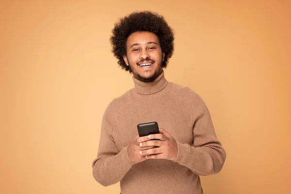 Smiling african american man using mobile phone in studio. People lifestyle concept.