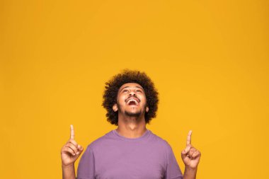 Mutlu gülümseyen afro adam sarı stüdyo arkasında poz veriyor..