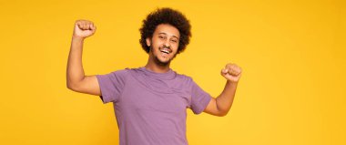 Mutlu gülümseyen afro adam sarı stüdyo arkasında poz veriyor..