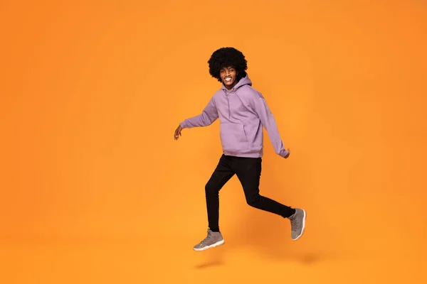 Uomo Felice Con Capelli Afro Saltando Sullo Sfondo Arancione — Foto Stock