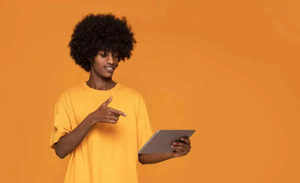 Cheerful Afro Man pointing on Tablet Screen .