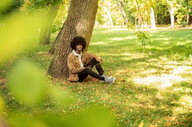 Parkta tablet kullanan genç bir Afrikalı Amerikalı..