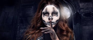 Siyah stüdyo arka planında kafatası makyajı olan bir kadının portresi. Cadılar Bayramı kostümü ve makyaj.