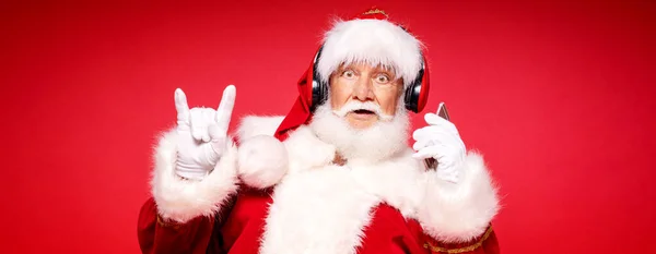 Zabawny Brodaty Prawdziwy Święty Mikołaj Słuchawkami Słuchającymi Muzyki Telefonu Komórkowego — Zdjęcie stockowe