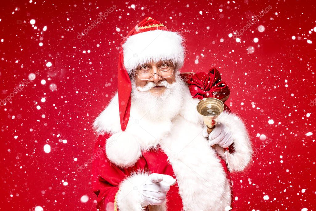 Christmas are coming! Real Santa Claus posing on red studio background.