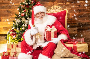Gerçek Noel Baba, Noel Ağacı 'nın yanında oturuyor. Güzel bir hediye ve altın ziliyle, gülümsüyor..
