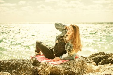 Plaj Bahamaları 'ndaki taşın üzerine uzanmış güzel bir kadının portresi.