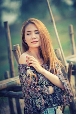 Off Shoulder tişörtlü ve kısa kotlu Asyalı bir kadın doğanın üzerinde duruyor.