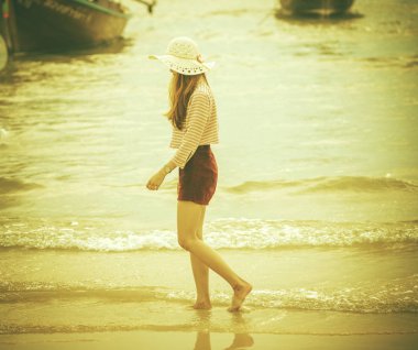 Sahilde yürüyen Asyalı kadın.