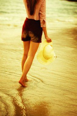 Sahilde yürüyen Asyalı kadın.