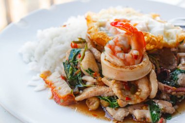 Tavada kızartılmış domuz eti, kalamar, karides, tavuk, gevrek domuz eti ve fesleğen ve kızarmış yumurta ile tepesinde pirinç.