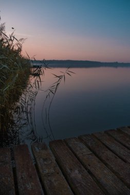 Güneşin doğuşunda sakin bir gölün üzerindeki ıssız iskelede