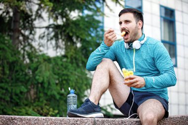 Genç yakışıklı adam meyve salatası koşu sonra keyif alıyor.