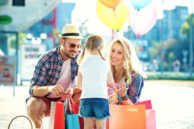 Mutlu aile alışveriş merkezi alışveriş torbaları ve balon ile boyunca yürüyüş.