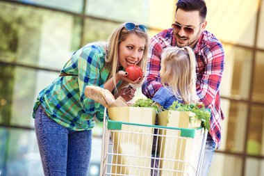 Genç gülümseyen veliler ve alışveriş sepeti taze gıda hipermarket önünde eğleniyor dolu ile şirin kızları.