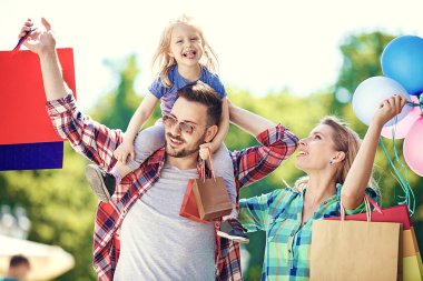 Mutlu aile alışveriş torbaları ile sokak boyunca yürüyüş.