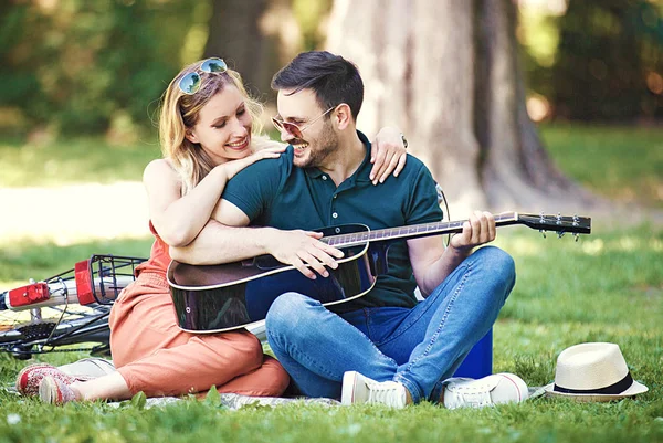 公園で座って ギターを弾くロマンチックな恋人のカップル — ストック写真