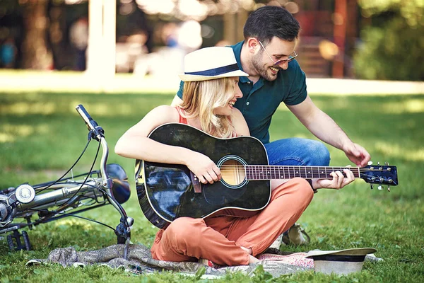 Parkta oturan ve gitar çalmak romantik aşıklar birkaç.