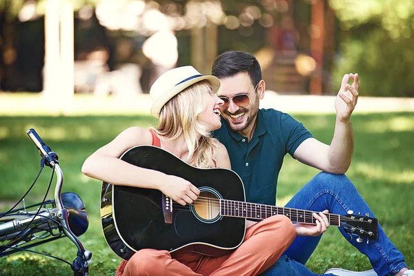 Parkta oturan ve gitar çalmak romantik aşıklar birkaç.
