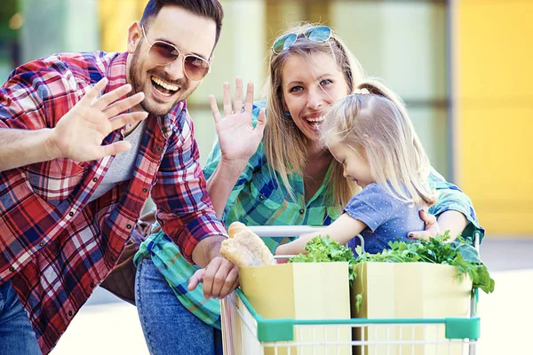 Unga Leende Föräldrar Och Deras Söta Dotter Med Kundvagn Full — Stockfoto