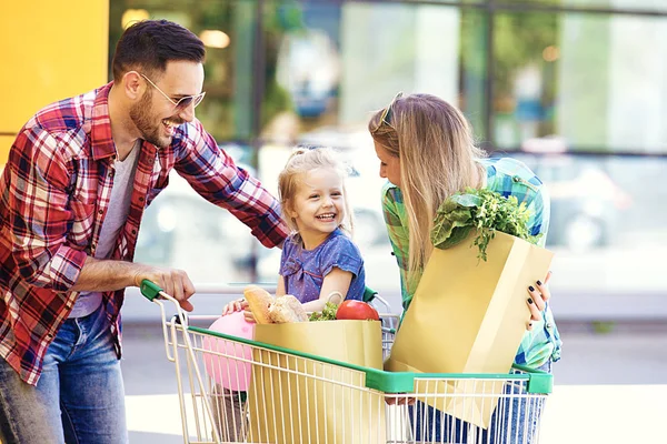 Genç gülümseyen veliler ve alışveriş sepeti taze gıda hipermarket önünde eğleniyor dolu ile şirin kızları.