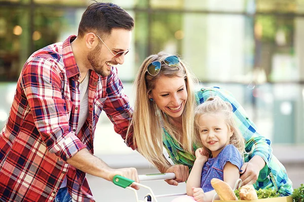 Genç gülümseyen veliler ve alışveriş sepeti taze gıda hipermarket önünde eğleniyor dolu ile şirin kızları.