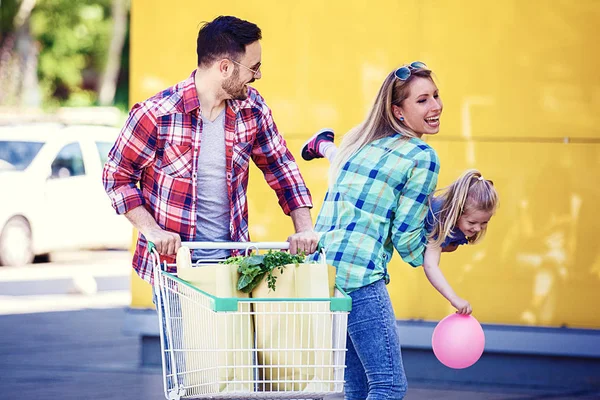 Unga Leende Föräldrar Och Deras Söta Dotter Med Kundvagn Full — Stockfoto