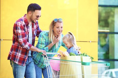 Genç gülümseyen veliler ve alışveriş sepeti taze gıda hipermarket önünde eğleniyor dolu ile şirin kızları.