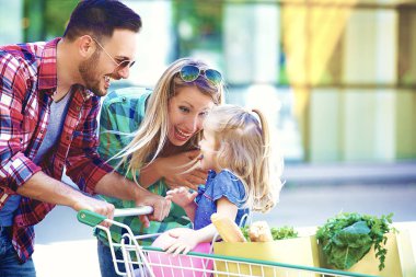 Genç gülümseyen veliler ve alışveriş sepeti taze gıda hipermarket önünde eğleniyor dolu ile şirin kızları.