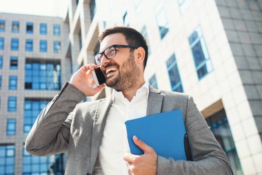 Genç işadamı cep telefonuyla, bina şirket önünde.