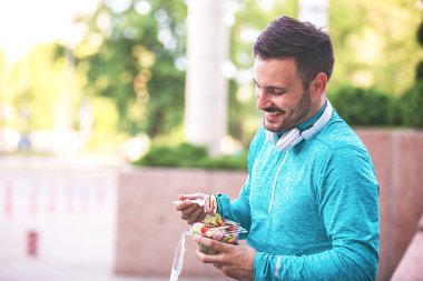 Yakışıklı delikanlı sebze salatası koşu sonra keyif alıyor.