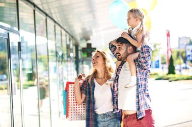 Mutlu aile alışveriş merkezi alışveriş torbaları ve balon ile boyunca yürüyüş.