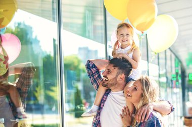 Mutlu aile alışveriş merkezi alışveriş torbaları ve balon ile boyunca yürüyüş.