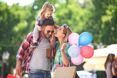 Mutlu aile alışveriş torbaları ile sokak boyunca yürüyüş.