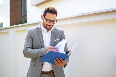 Genç işadamı, bina şirket önünde grafik bakarak.